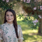 Woman in a pink floral dress standing in front of pink flowers.