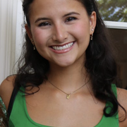 A smiling woman in a green sleeveless shirt with a name tag.