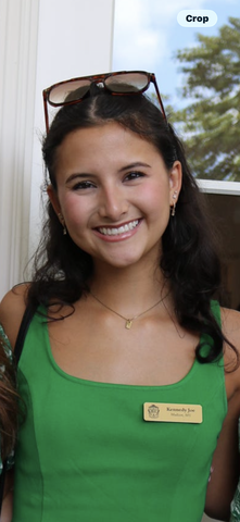 A smiling woman in a green sleeveless shirt with a name tag.