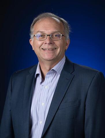 Formal portrait of Richard Bucholz; bright blue background