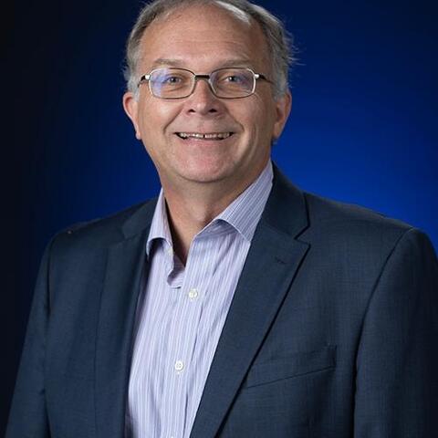 Formal portrait of Richard Bucholz; bright blue background