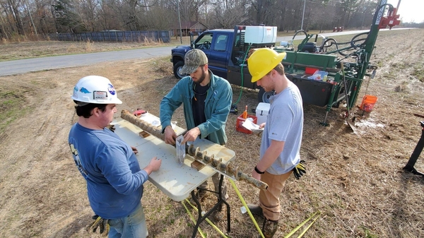 three students collecting core from a drill rig