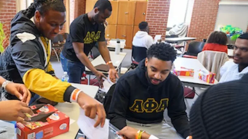 people gathered around a table, some sitting, some standing all with a lot of activity